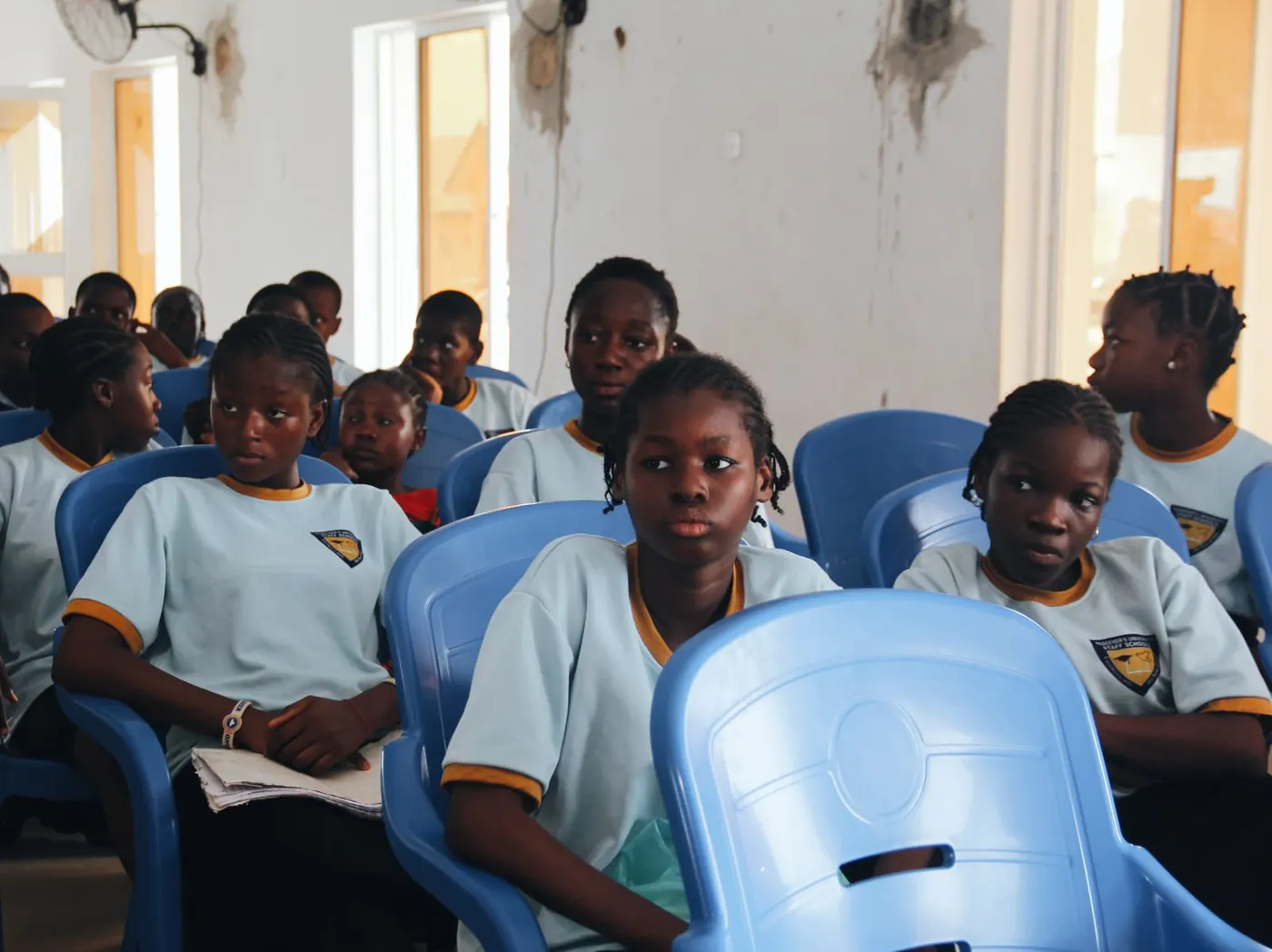 Secondary school girls in light blue uniforms listening during a Project GIRL Again session